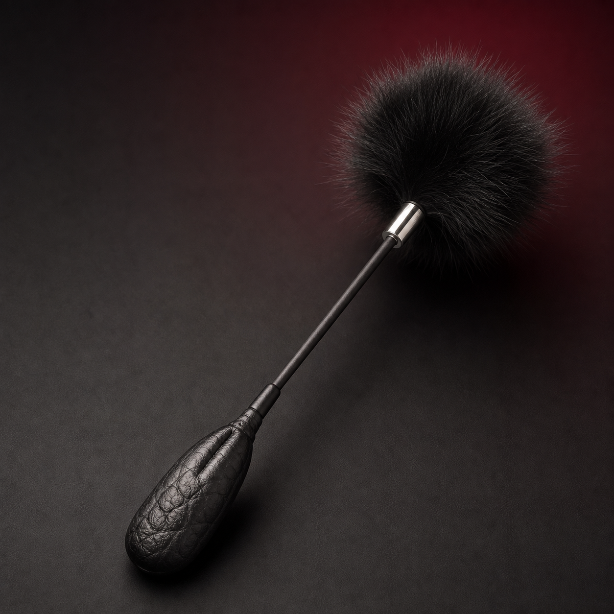 Close-up of the fluffy black feather head, silver-tone collar, slim shaft, and crinkle-texture leather grip.