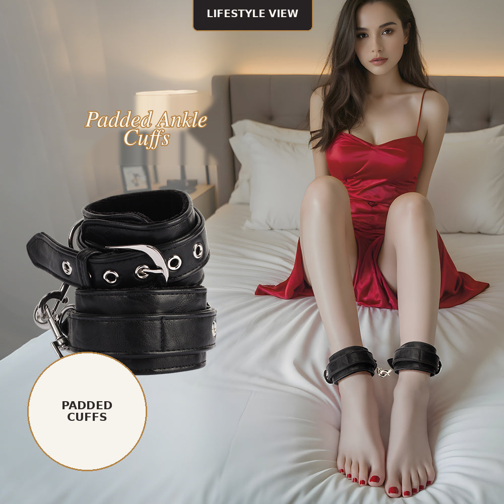 A lifestyle shot of a model sitting on a bed wearing black padded ankle cuffs, with a separate stack of the black cuffs shown on the left. The model is wearing a red satin slip dress, and the scene is set in a bedroom with white bedding and a gray headboard.