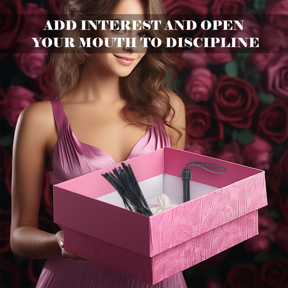 A woman in a pink satin dress holds an open pink gift box containing black hair ties and a small white item, with a dark rose-patterned background and the text 'ADD INTEREST AND OPEN YOUR MOUTH TO DISCIPLINE' across the top.