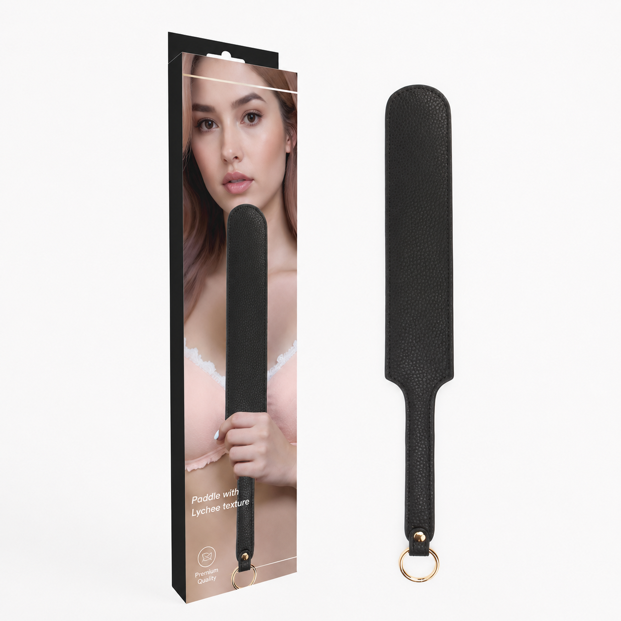 A black textured paddle-style strap with a gold-tone ring at the handle, shown next to its retail packaging box on a plain white background.