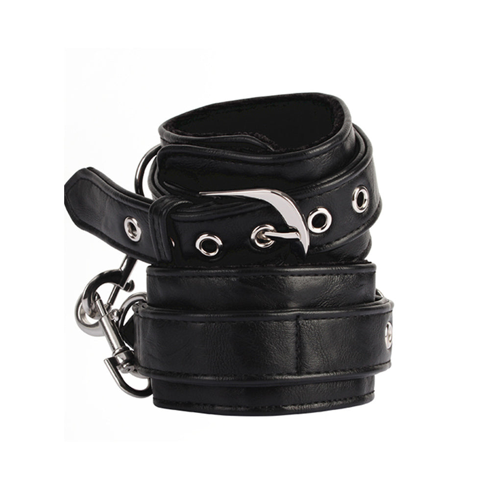 Pair of black adjustable padded wrist cuffs with silver-tone metal rings and hardware on a white background