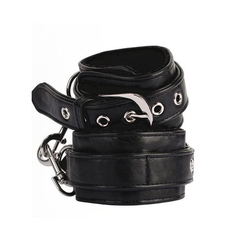 Pair of black adjustable padded wrist cuffs with silver-tone metal rings and hardware on a white background